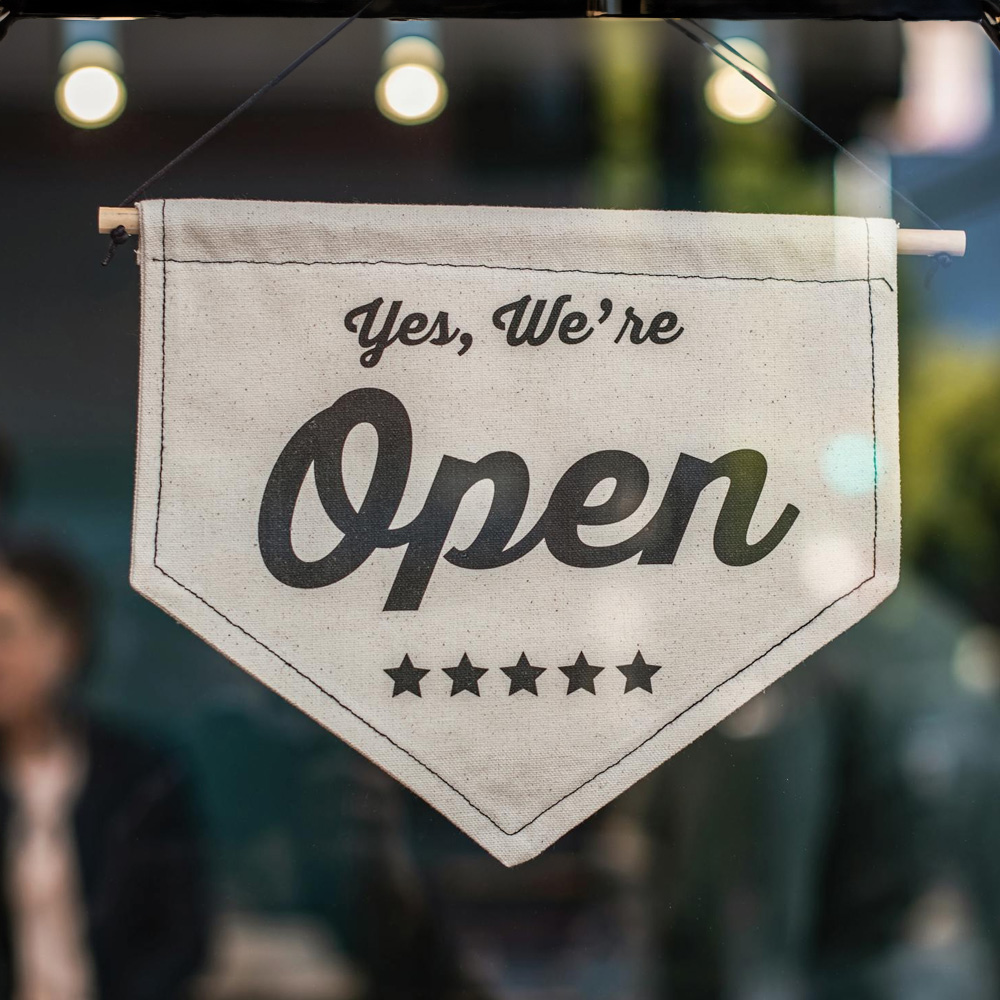 Photo of a sign in a window that says "Yes, we're open"
