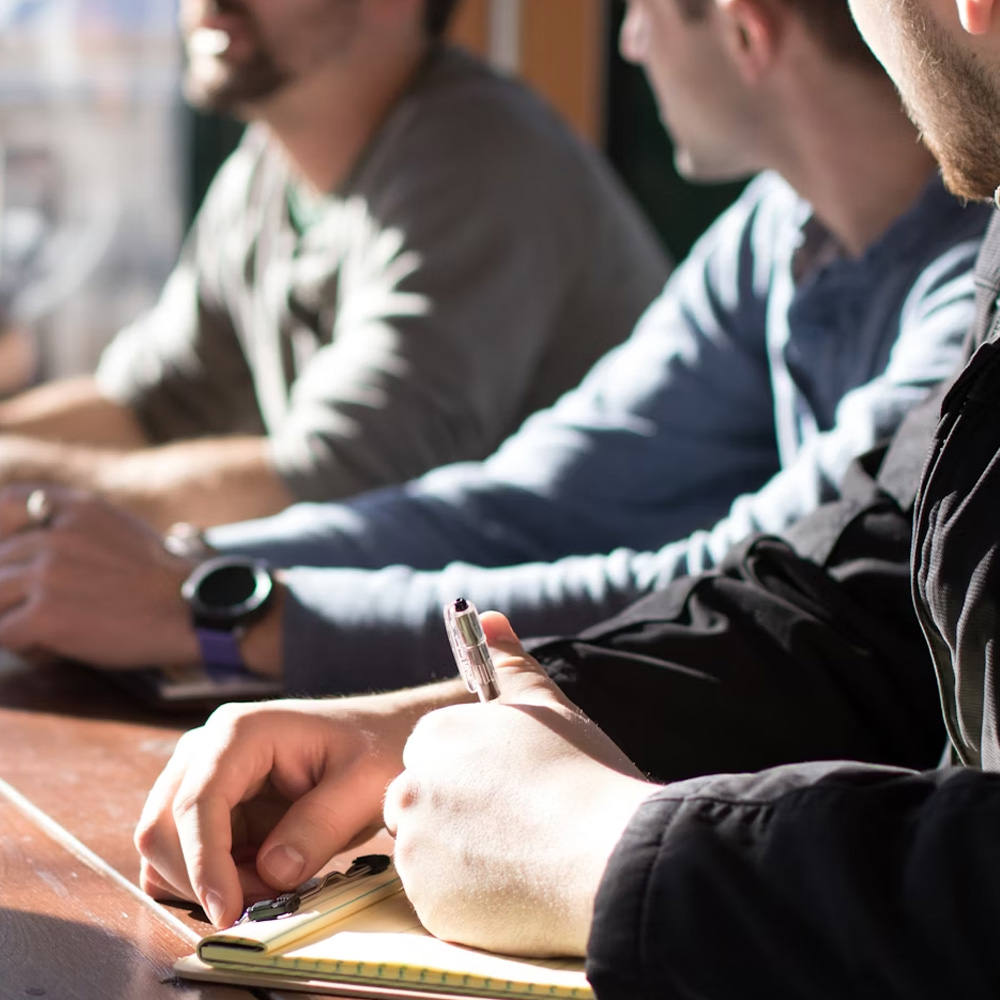 Photo of people sitting at conference table taking notes